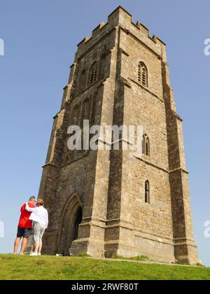 Besucher blicken auf den Turm der Kirche St. Michael aus dem 14. Jahrhundert am Glastonbury Tor, Glastonbury, Somerset, Großbritannien. Stockfoto