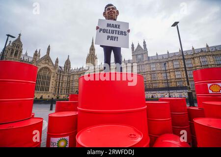 London UK. 19 . September 2023 . Ein Modell mit einem riesigen Kopf von Premierminister Rishi Sunak auf BP- und Shell-Ölfässern während eines Oxfam-Protestes vor dem Parlament als Teil der Kampagne Make Polluters Pay, Oxfam fordert Öl- und Gasriesen stärker zu besteuern, um Gemeinden, die vom Klimawandel betroffen sind, zu unterstützen. Credit amer ghazzal/Alamy Live News Stockfoto