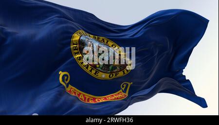 Nahaufnahme der Flagge des Staates Idaho, die an einem klaren Tag im Wind winkt. Staatssiegel in einem dunkelblauen Bereich mit den Worten "Staat Idaho" in goldenen Buchstaben Stockfoto