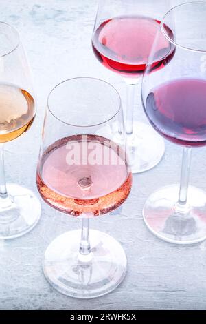 Weingläser bei einer Verkostung. Rose-, Rot- und Weißwein, Getränke auf einem Steintisch. Eine Auswahl an Weinen in vielen verschiedenen Farben Stockfoto