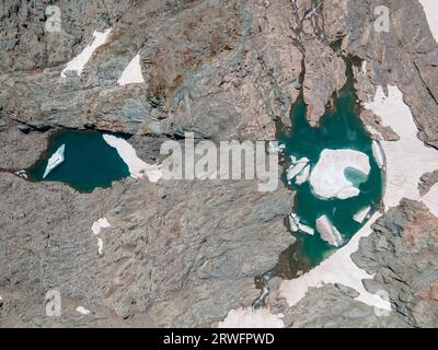 Drone von oben nach unten Blick auf Gletscherseen im Berg mit gefrorenem Wasser und Eisbergen, felsigem Boden. Ciamarella-Gletscher Stockfoto