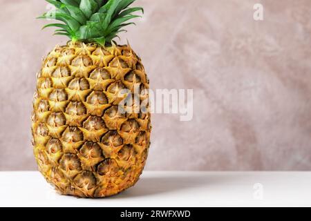 Köstliche reife Ananas auf weißem Tisch nahe der rosa Wand, Nahaufnahme. Leerzeichen für Text Stockfoto
