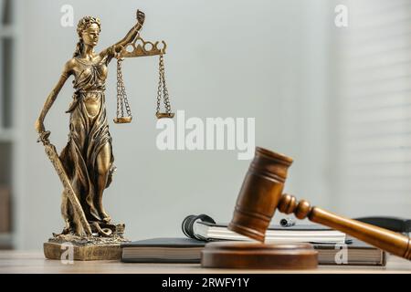 Figur der Lady Justice, Hammer und Notizbücher auf dem Tisch drinnen, Platz für Text. Symbol der gerechten Behandlung nach dem Gesetz Stockfoto