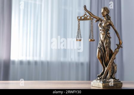 Figur der Lady Justice auf Holztisch im Innenbereich, Platz für Text. Symbol der gerechten Behandlung nach dem Gesetz Stockfoto