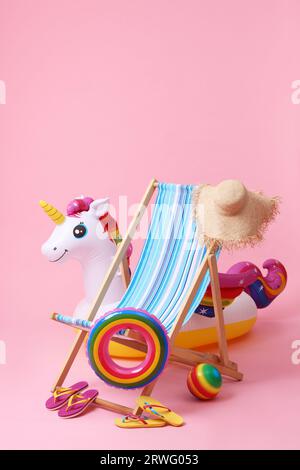 Liegestühle, Flip Flops und andere Strandaccessoires auf rosa Hintergrund. Sommerferien Stockfoto