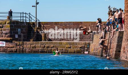 Kinder, die bei heißem Sommerwetter vom Kai ins Meer springen, North Berwick Harbour, East Lothian, Schottland, Großbritannien Stockfoto