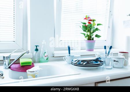 Ungewaschenes Geschirr auf einem Stapel auf dem Küchentisch in der Nähe des Waschbeckens Stockfoto