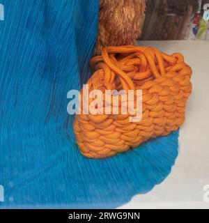 Eine orangefarbene Tasche aus großer Jute in der Nähe eines blauen Kleides Stockfoto