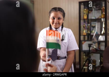 Happy Proud Principal, Lehrer persönlich schenkt, bietet indische Flagge als Geschenk an, Auszeichnung an eine Schülerin für ihre Beförderung in der Schule. Stockfoto