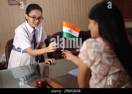 Glücklicher, stolzer Direktor, Lehrer persönlich, der indische Flagge als Belohnung anbietet. Belohnung an die Schülerin für ihre Beförderung in der Schule. Patriotismus. Stockfoto