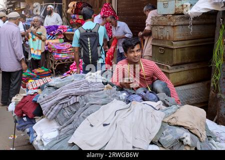 Ein Mann, der viele Second-Hand-Kleidung im Freien auf einer Straße im beliebten Chor-Basar (Dieves' Market) im Bhendi-Basar-Gebiet, Mumbai, Indien, verkauft Stockfoto