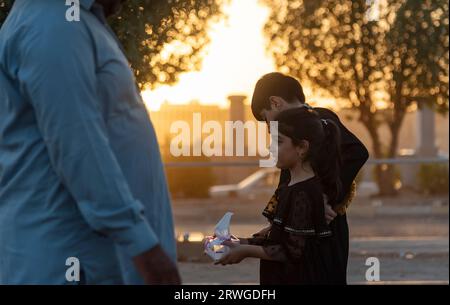 Najaf, Irak. September 2023. Ein irakisches schiitisches Mädchen verteilt Gewebepapiere unter schiitischen Pilgern, die von Najaf in Richtung der Schreinerstadt Karbala marschieren. Jedes Jahr pilgern Millionen schiitische Muslime und einige aus anderen Glaubensrichtungen zu Fuß von verschiedenen Städten im Irak und Iran in die heilige Stadt Karbala. Diese Pilgerfahrt erinnert an Imam Hussein, den Enkel des Propheten Mohammed, der 680 n. Chr. in einer Schlacht starb. Am 40. Tag der Trauer um Hussein, bekannt als Arbaeen, kommen Pilger in Karbala zusammen, um an seinem Heiligtum Tribut zu zollen. Auf dem Weg stellen Freiwillige Nahrung zur Verfügung Stockfoto