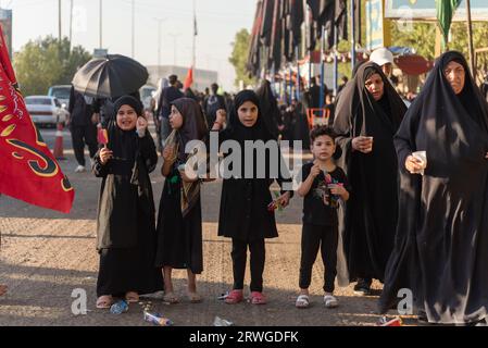 Najaf, Irak. September 2023. Irakische schiitische Mädchen brüllen religiöse Parolen, während schiitische Pilger von Najaf in Richtung der Heiligstadt Karbala marschieren. Jedes Jahr pilgern Millionen schiitische Muslime und einige aus anderen Glaubensrichtungen zu Fuß von verschiedenen Städten im Irak und Iran in die heilige Stadt Karbala. Diese Pilgerfahrt erinnert an Imam Hussein, den Enkel des Propheten Mohammed, der 680 n. Chr. in einer Schlacht starb. Am 40. Tag der Trauer um Hussein, bekannt als Arbaeen, kommen Pilger in Karbala zusammen, um an seinem Heiligtum Tribut zu zollen. Auf dem Weg stellen Freiwillige Nahrung, Wasser, Stockfoto