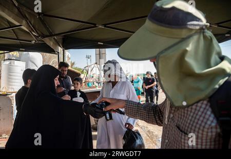 Najaf, Irak. September 2023. Eine iranische schiitische Frau verteilt Wasser unter schiitischen Pilgern, die von Najaf in Richtung der Heiligstadt Karbala marschieren. Jedes Jahr pilgern Millionen schiitische Muslime und einige aus anderen Glaubensrichtungen zu Fuß von verschiedenen Städten im Irak und Iran in die heilige Stadt Karbala. Diese Pilgerfahrt erinnert an Imam Hussein, den Enkel des Propheten Mohammed, der 680 n. Chr. in einer Schlacht starb. Am 40. Tag der Trauer um Hussein, bekannt als Arbaeen, kommen Pilger in Karbala zusammen, um an seinem Heiligtum Tribut zu zollen. Auf dem Weg stellen Freiwillige Nahrung und Wasser zur Verfügung Stockfoto