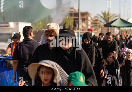 Najaf, Irak. September 2023. Schiitische muslimische Pilger marschieren von Najaf in Richtung der Schreinerstadt Karbala. Jedes Jahr pilgern Millionen schiitische Muslime und einige aus anderen Glaubensrichtungen zu Fuß von verschiedenen Städten im Irak und Iran in die heilige Stadt Karbala. Diese Pilgerfahrt erinnert an Imam Hussein, den Enkel des Propheten Mohammed, der 680 n. Chr. in einer Schlacht starb. Am 40. Tag der Trauer um Hussein, bekannt als Arbaeen, kommen Pilger in Karbala zusammen, um an seinem Heiligtum Tribut zu zollen. Auf dem Weg stellen Freiwillige Nahrung, Wasser und Unterschlupf bereit, und die Dorfbewohner öffnen ihr Doo Stockfoto