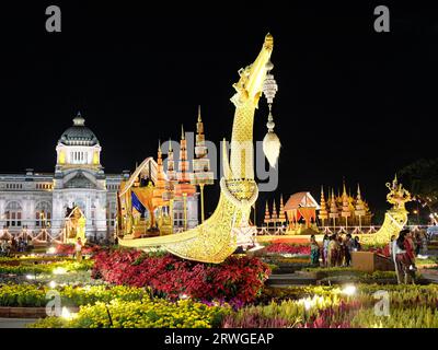 Bangkok, Thailand, 27. Dezember 2018. Ein goldenes Boot, umgeben von Blumen vor dem Hintergrund der thailändischen Architektur. Bunte asiatische Feierlichkeiten. Stockfoto