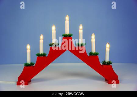 Traditioneller Weihnachtskerzenhalter mit sieben Kerzen auf blauem Winterhintergrund. Weihnachtskerzenbrücke mit sieben Kerzenlichtern. Dekoration für t Stockfoto