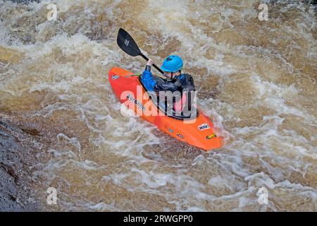 Kanufahren im orangen Kanu auf den Stromschnellen Whitewater Slalom Kanufahren im River Tryweryn im National Whitewater Centre in der Nähe von Bala North Wal Stockfoto