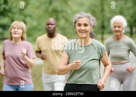 Ältere Frau, die mit ihren Freunden im Park läuft Stockfoto