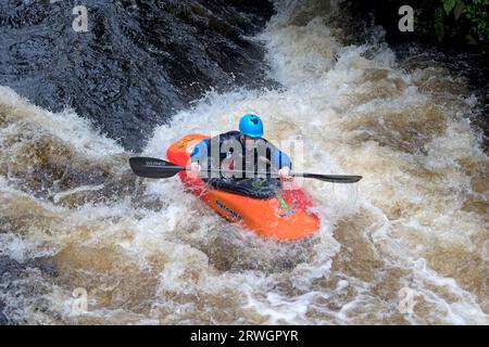 Kanufahren im orangen Kanu auf den Stromschnellen Whitewater Slalom Kanufahren im River Tryweryn im National Whitewater Centre in der Nähe von Bala North Wal Stockfoto