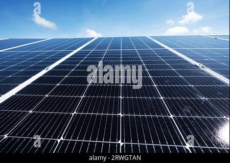 Sauberes Solarpaneel-Array auf blauem Himmelshintergrund mit kleinen Wolken Stockfoto