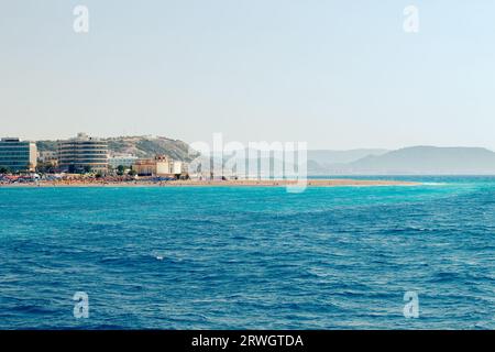 Beliebter Elli Strand oder Paralia Enidriou auf der Insel Rhodos in Griechenland, Europa. Beliebter Sandstrand in der Stadt an sonnigen Sommertagen, blauer Himmel. Vom Meer aus gesehen. Stockfoto
