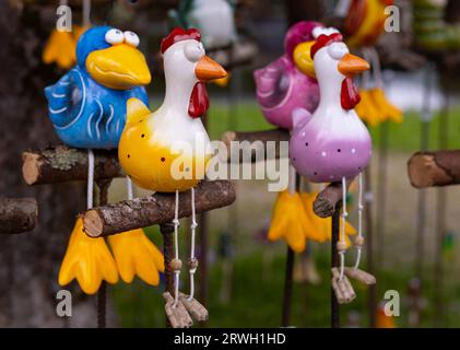 Auf dem Straßenmarkt werden helle Keramikspielzeugvögel auf Holzbarschen verkauft Stockfoto