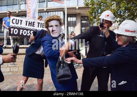 London, Großbritannien. September 2023. Demonstranten, die als Führungskräfte von Unternehmen mit fossilen Brennstoffen verkleidet sind, stopfen gefälschtes Geld in die Tasche eines Demonstranten, der eine Maske des Labour-Parteivorsitzenden Keir Starmer trägt, während die Extinction Rebellion einen Protest gegen neue fossile Brennstoffe inszeniert. Stockfoto