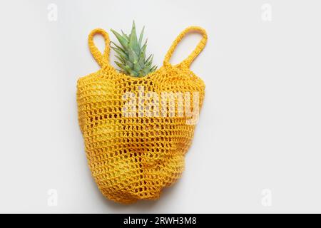 Grüner Salat und Früchte in einem gelblichen Öko-Säckchen auf weißem Hintergrund. Lauch, Salat, Ananas. Stockfoto