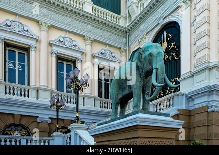 Eine große Elefantenstatue steht auf einem aufwendig gemusterten Sockel vor einem kunstvoll gestalteten Gebäude. Stockfoto