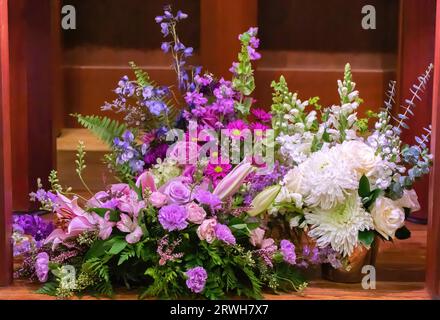 Drei wunderschöne Blumenarrangements in St. Josephs katholische Kirche unter dem Altar; zur Dekoration der Kirche nach einer Beerdigung. Stockfoto