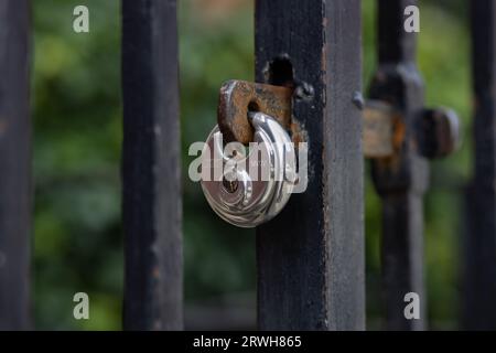 Metallvorhängeschlösser an den Eingangstoren zu Häusern, Gärten und Parks, alte Vorhängeschlösser, die an den Toren hängen, grafischer Hintergrund, kreatives Design, Nahaufnahme Foto. Stockfoto