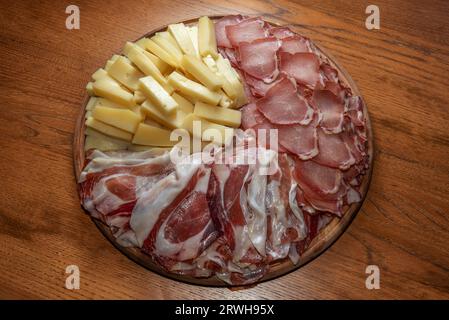 Wurst- und Käseplatte mit Blick von oben. Schinkenscheiben und Salami mit Käsestückchen auf Holzbrett auf Holzbrett Stockfoto
