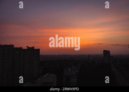 Sonnenaufgang über der Stadt. Morgengradientenhimmel über Kiew, Ukraine. Morgenhimmel in der Abenddämmerung über Gebäuden. Himmel am Abend in der Innenstadt. Malerischer Sonnenuntergangshimmel Stockfoto