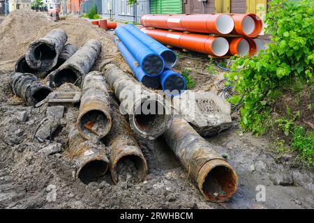 Austausch der unterirdischen Wasserversorgung und Abwasserleitungen in der Stadtstraße, schmutzige alte Rohre neben neuem blauen Plastikwasser und braunen Abwasserleitungen Stockfoto