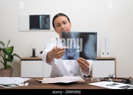 Die Ärztin spricht mit dem Patienten online, der mit dem Finger auf die Pathologie auf dem Röntgenbild zeigt Stockfoto