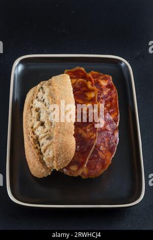 Ansicht eines Chorizo ​​sandwich von oben auf einem dunklen Tablett, isoliert auf schwarzem Hintergrund Stockfoto