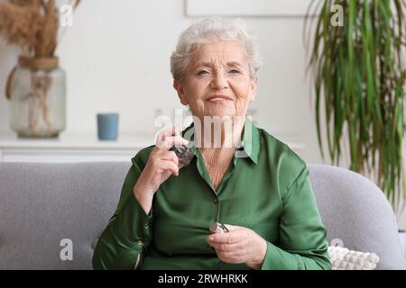 Seniorin, die zu Hause Parfüm aufträgt Stockfoto
