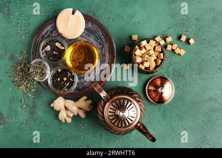Komposition mit Vintage-Teeset aus Messing und verschiedenen Teesorten auf grünem Tisch Stockfoto