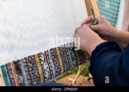 Teppichweberei mit traditionellen Techniken auf einem Webstuhl. , Nahaufnahme von Weben und handgefertigten Teppich Produktion. Stockfoto