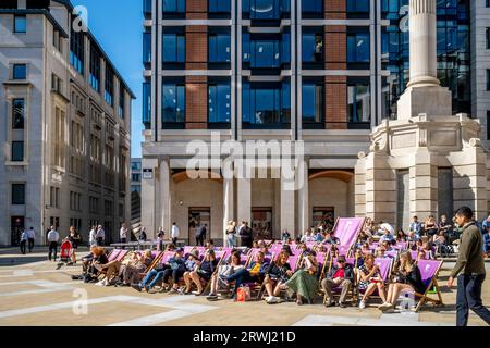 Leute, die auf Liegestühlen sitzen, genießen das Sunshine, Paternoster Square, die City of London, London, Großbritannien. Stockfoto