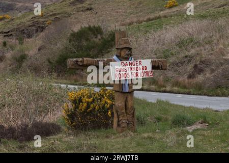 Schottland, Großbritannien - 29. April 2023 - Vogelscheuche mit einem Schild am Straßenrand, das besagt, dass die Straßen für 16 Meilen nicht den Standards entsprechen Stockfoto