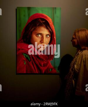 Eine Frau schaut sich Steve McCurrys ikonisches Foto eines afghanischen Mädchens an Stockfoto