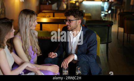Junger attraktiver Mann, der mit seinen Freunden im Restaurant sitzt und die Rechnung per Kreditkarte bezahlt. Lifestyle- und Freundschaftskonzept. Zeitlupe Stockfoto