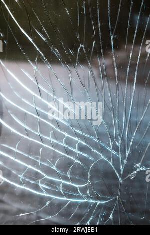 Rissige Glasscheibe aus der Nähe. Dies ist eine Glasoberfläche mit vielen Rissen durch Aufprall. Hintergrund. Stockfoto