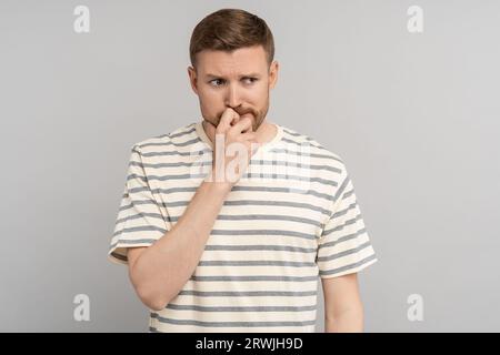 Gestresster, aufmerksamer Mann, der an eine Problemlösung denkt, müde mit einem unglücklichen Gesichtsausdruck Stockfoto