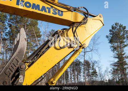 CROW WING CO, MN - 3. MAI 2023: Komatsu Baggerarm, Winkelstück und Hydraulikschläuche an einer schweren Arbeitsmaschine, an einem neuen Hausbau Stockfoto