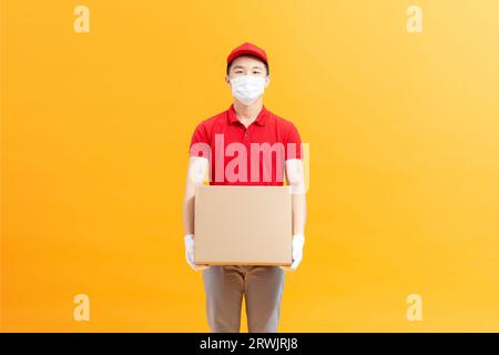 Liefermann, Der Karton Hält, Der Das Postpaket Mit Medizinischer Maske Liefert Stockfoto