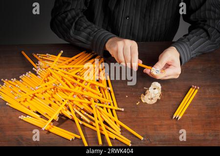 Mann, die Stifte mit einem Bleistiftspitzer schärfen Stockfoto