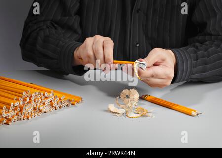 Mann, der einen Haufen Bleistifte mit einem Bleistiftspitzer schärft Stockfoto